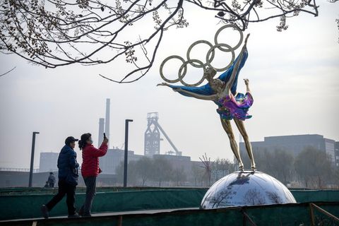 Besucher fotografieren eine Statue von Eiskunstläufern mit den olympischen Ringen