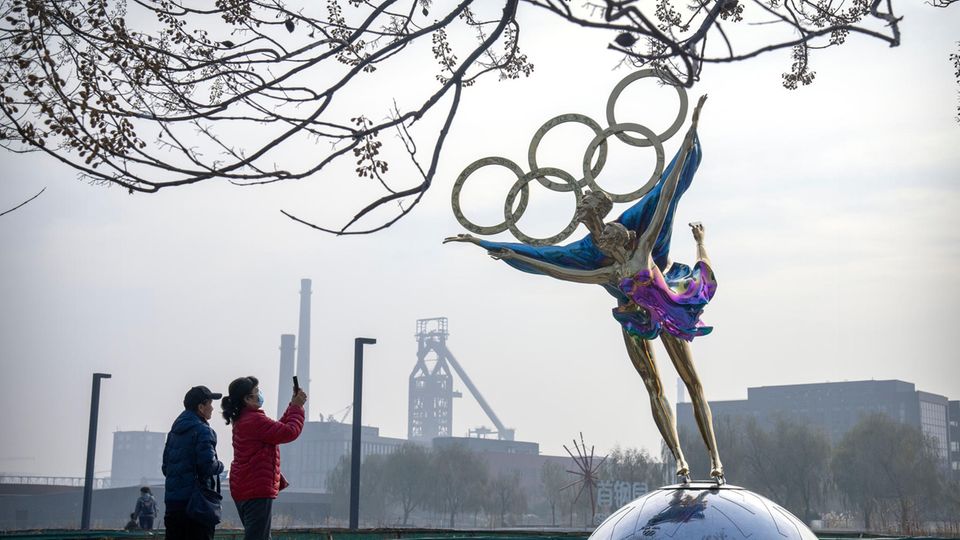 Besucher fotografieren eine Statue von Eiskunstläufern mit den olympischen Ringen