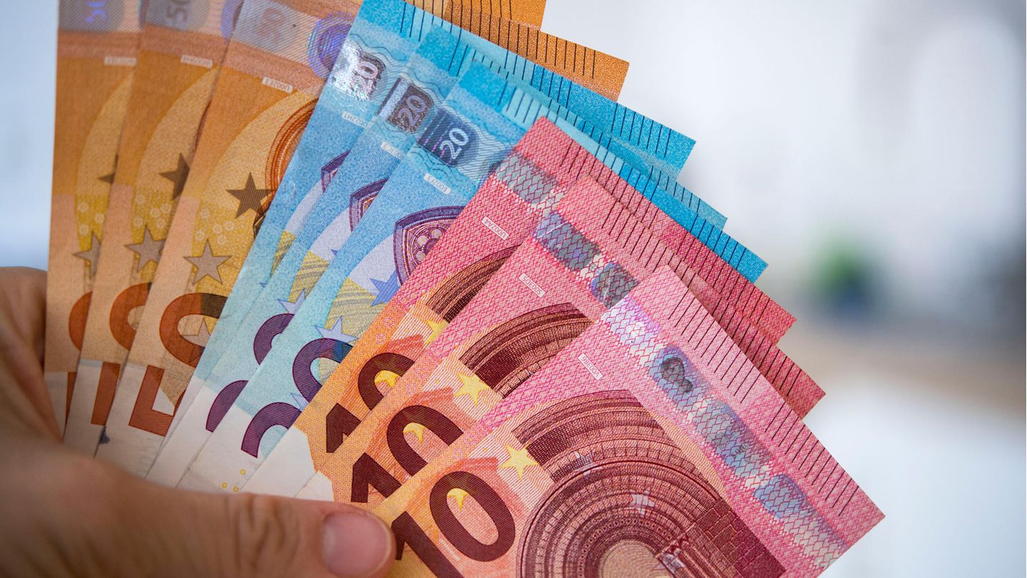 Die linke Hand einer Frau hält aufgefächert 10-, 20- und 50-Euro-Scheine