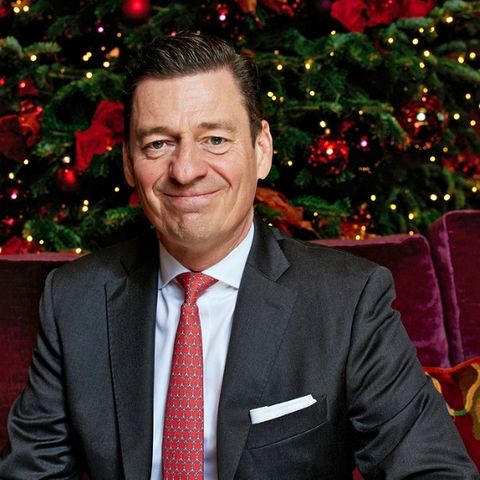 Hoteldirektor Ingo C. Peters sitzt vor einem Weihnachtbaum und lächelt
