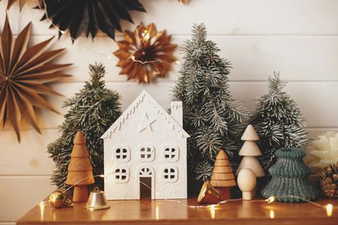 Skandinavische Weihnachtsdeko: Weihnachtshaus, Holzbäume, goldene Lichter und Papiersterne