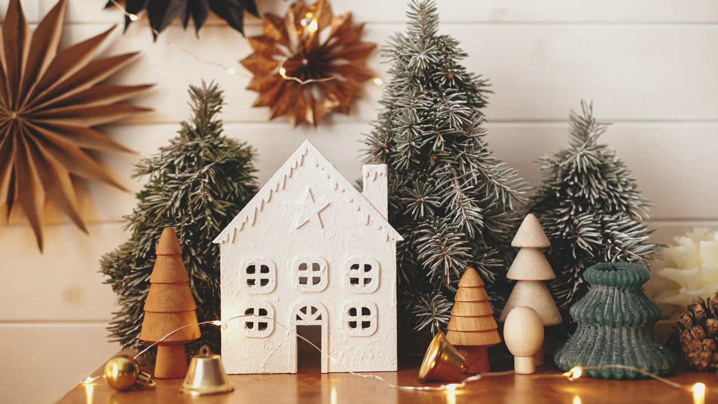 Skandinavische Weihnachtsdeko: Weihnachtshaus, Holzbäume, goldene Lichter und Papiersterne