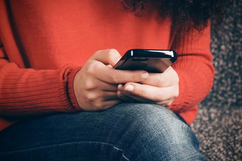 Eine Jugendliche tippt etwas in ihr Handy ein
