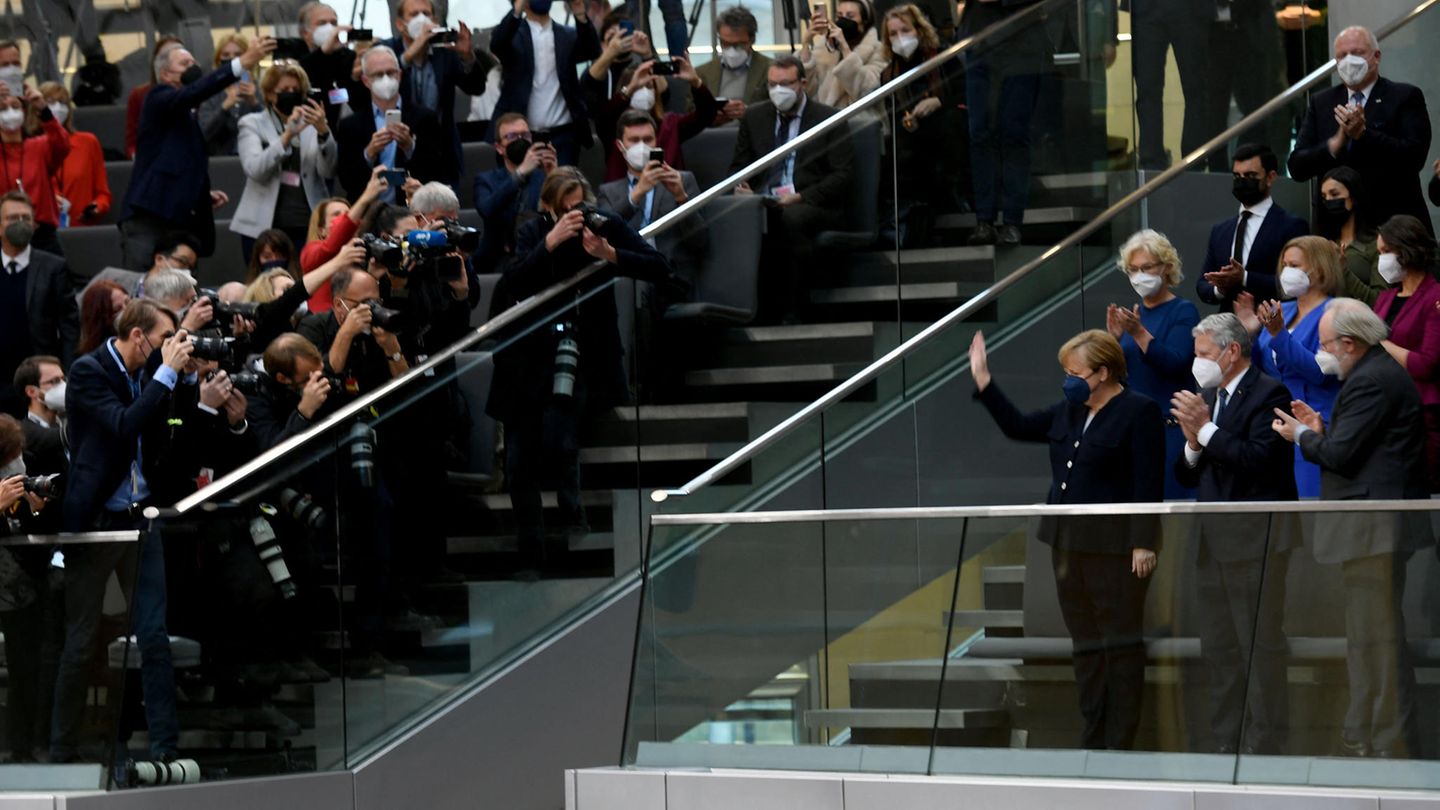 Angela Merkel steht und winkt auf der Tribüne des Bundestages