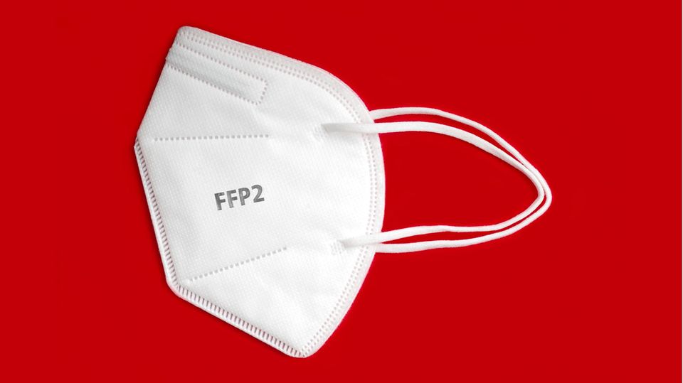 Weiße FFP2-Maske liegt auf rotem Grund
