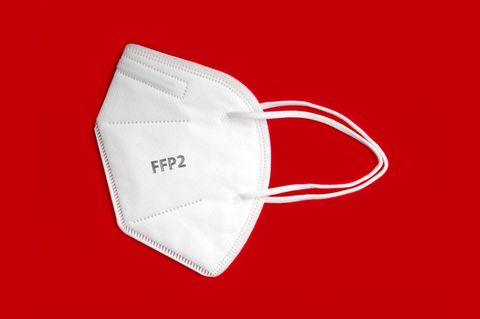 Weiße FFP2-Maske liegt auf rotem Grund