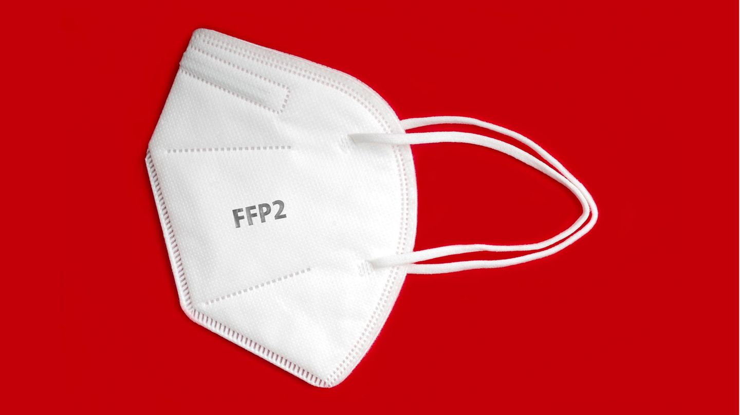 Weiße FFP2-Maske liegt auf rotem Grund