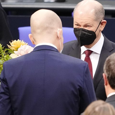 Olaf Scholz bei seiner Vereidigung, vor ihm ein Gratulant mit Blumenstrauß