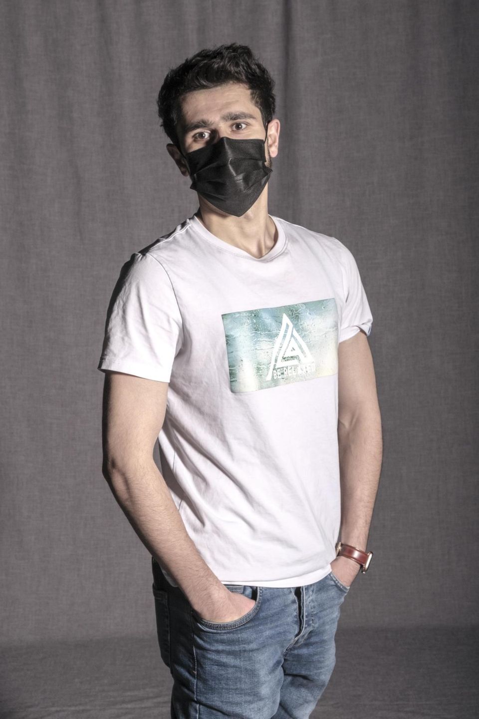 Geflüchteter Ozair A. in weißem T-Shirt und den Händen in den Taschen der Jeanshose