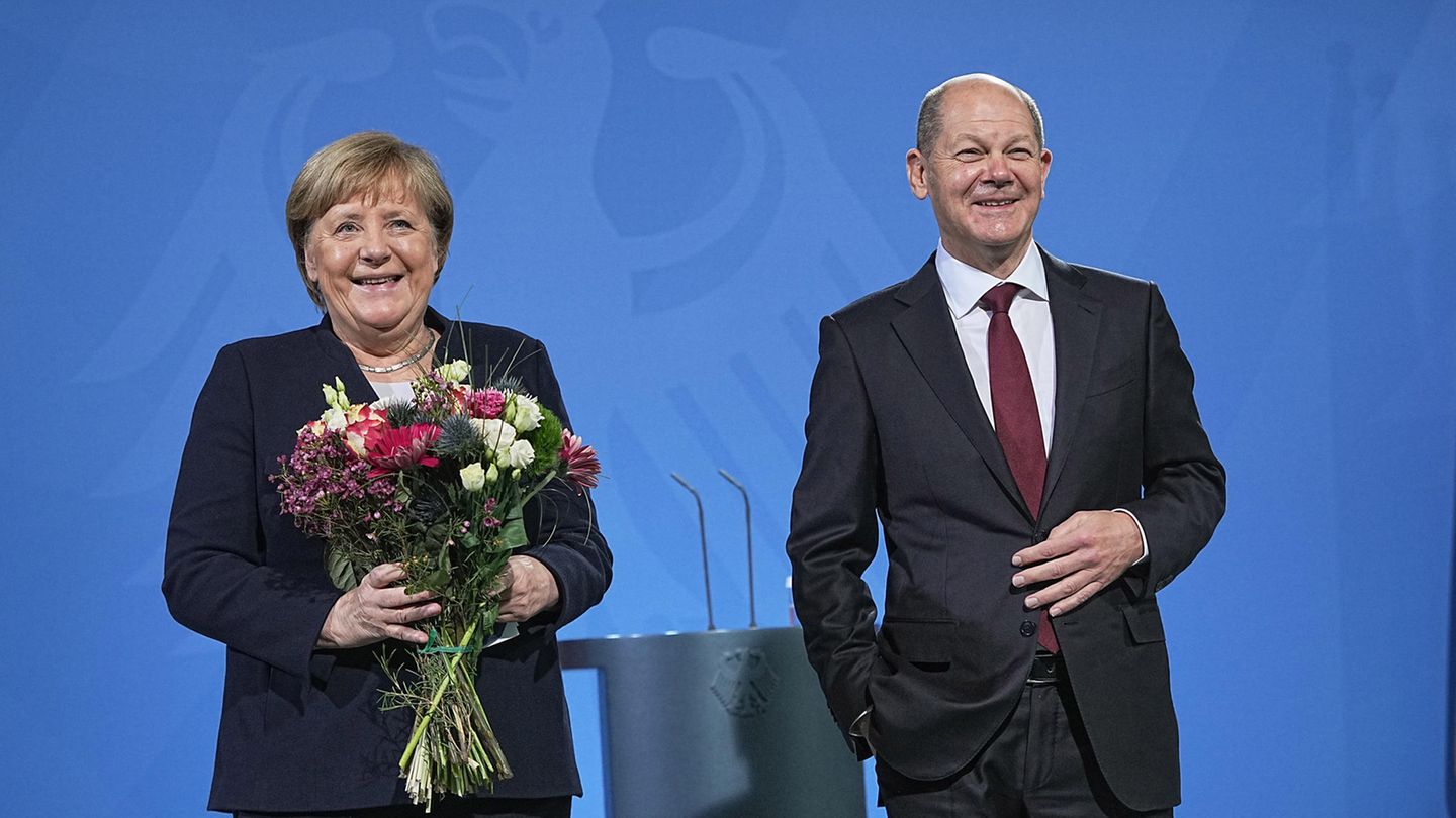 Bundeskanzler Olaf Scholz übergibt einen Strauss Blumen bei der Amtsübergabe der bisherigen Bundeskanzlerin Angela Merkel (CDU)