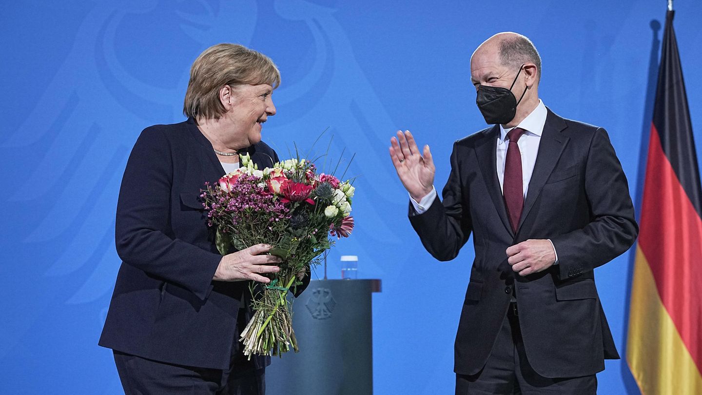 Angela Merkel hält einen Blumenstrauß in den Händen bei der Amtsübergabe an den neuen Bundeskanzler Olaf Scholz. 