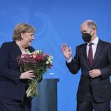 Merkel hält Blumen in den Händen - Scholz hebt die Hand zum Dank