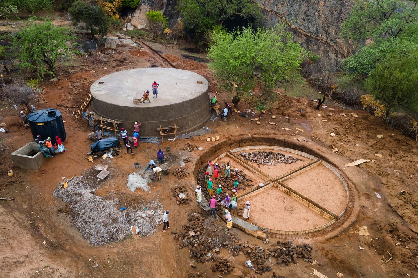 Männer und Frauen aus Kinakoni arbeiten an zwei jeweils 225 Kubikmeter fassenden Wassertanks