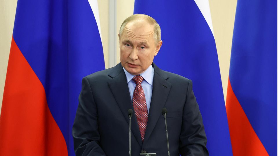 Wladimir Putin vor Russischen Flaggen am Podium