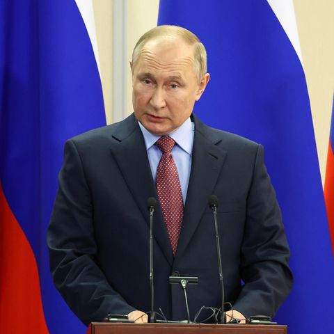 Wladimir Putin vor Russischen Flaggen am Podium