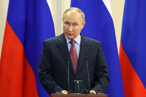 Wladimir Putin vor Russischen Flaggen am Podium