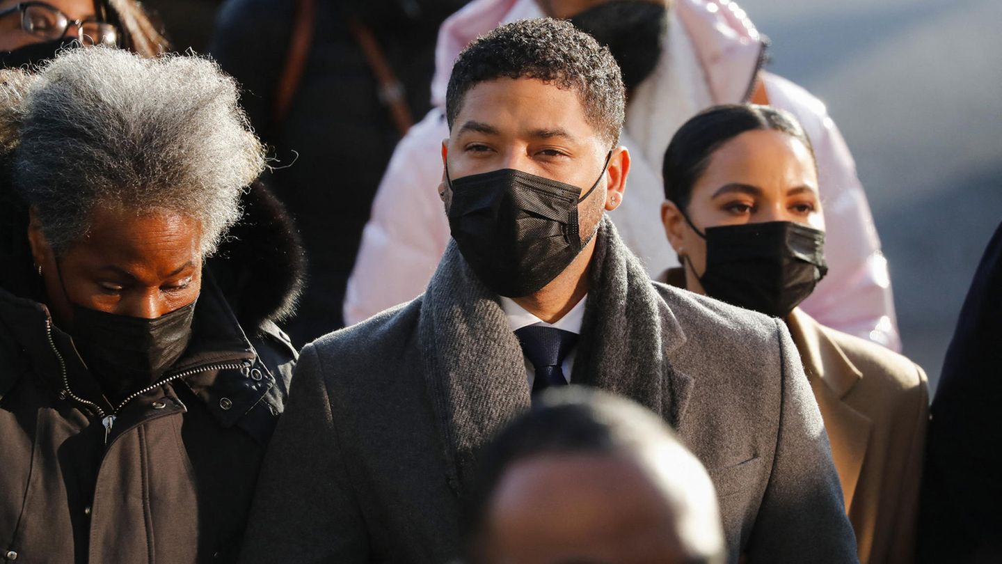 Jussie Smollett steht in einer Gruppe von Menschen und trägt einen Mund-Nasen-Schutz