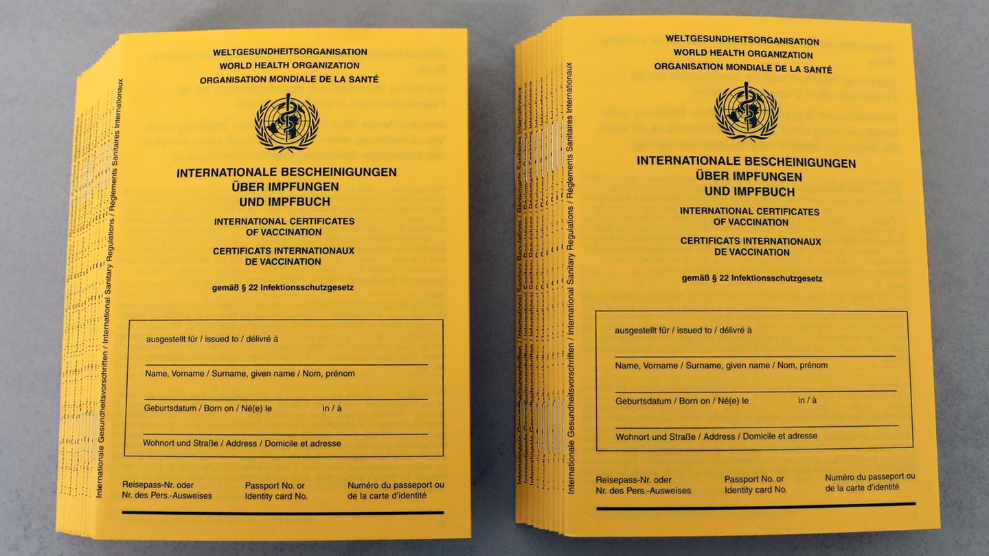 Auf zwei Stapeln liegen gelbe Impfpässe mit dem Logo der WHO und noch ohne Namenseintrag auf dem Deckblatt