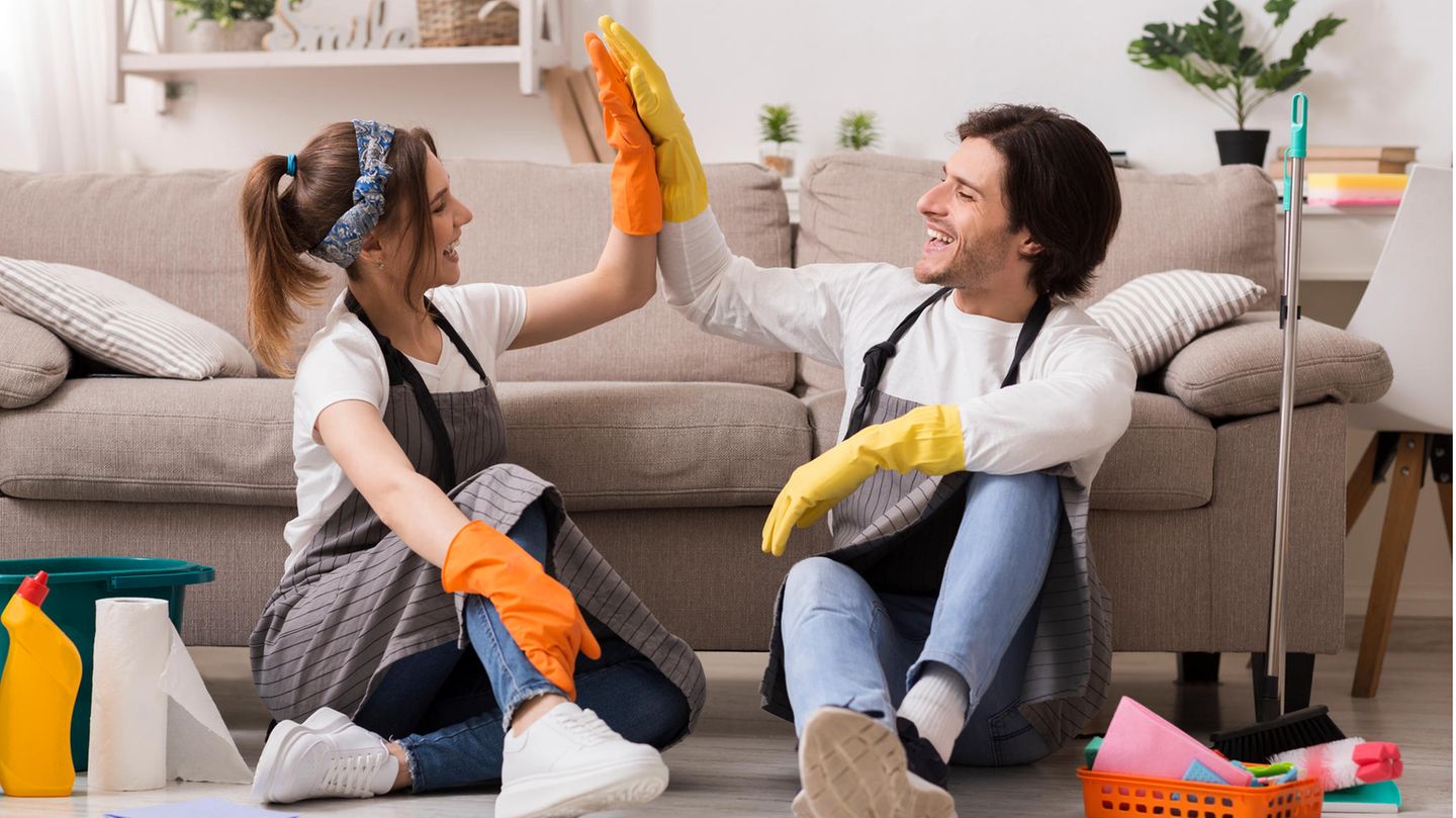 Mann und Frau geben sich zwischen Putzsachen ein High-Five Mann und Frau geben sich zwischen Putzsachen ein High-Five