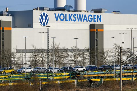 Autos stehen auf einem Transport-Zug vor einem VW-Gebäude
