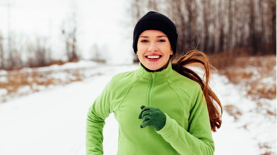 Eine Frau joggt im Schnee