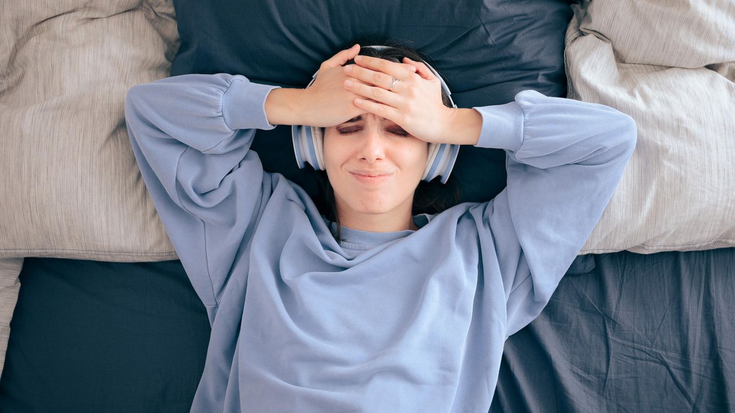 Eine Frau liegt im Bett und hört Musik