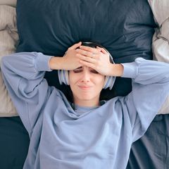 Eine Frau liegt im Bett und hört Musik