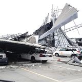 Auf dem Parkplatz stehen Autos, die von Wänden und Teilen des Daches getroffen wurden.
