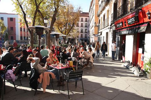Menschen genießen die Sonne vor einer Bar in der Innenstadt von Madrid