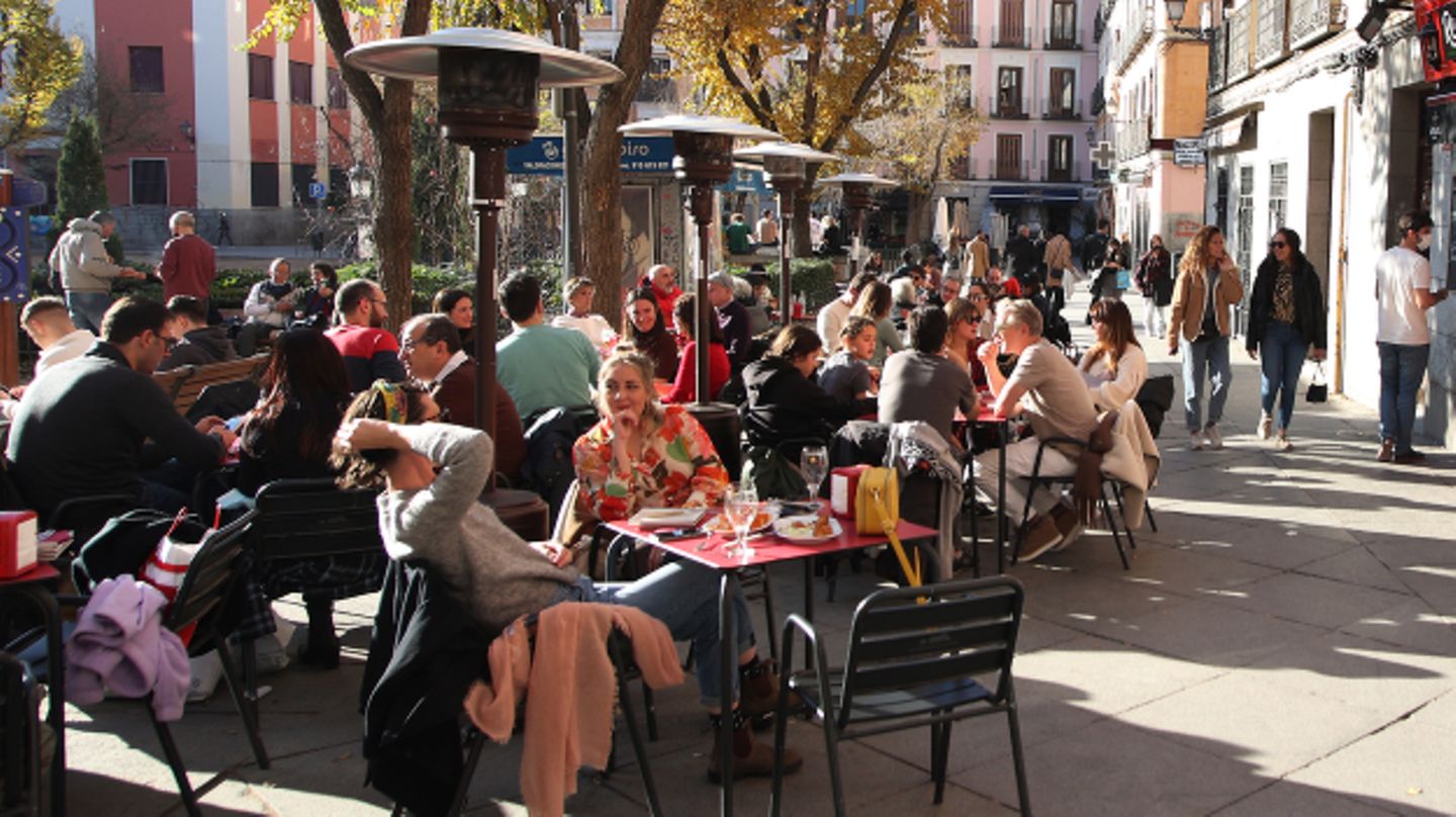 Menschen genießen die Sonne vor einer Bar in der Innenstadt von Madrid