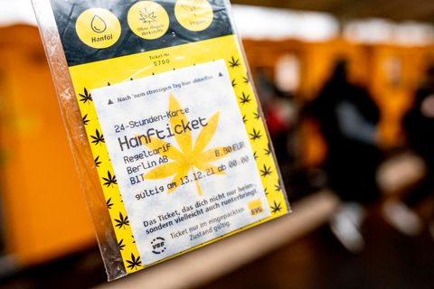 In einem durchsichtigen Tütchen ist ein "Hanfticket" der BVG vor einer Berliner U-Bahn zu sehen