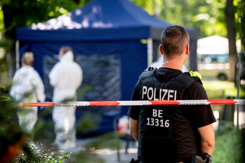 Ein Polizeibeamter und Mitarbeiter der Spurensicherung, im Hintergrund ein blaues Zelt