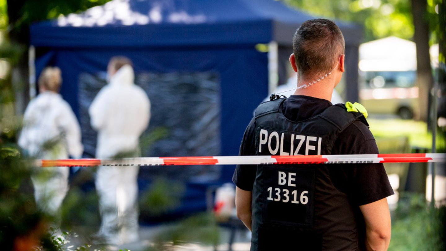 Ein Polizeibeamter und Mitarbeiter der Spurensicherung, im Hintergrund ein blaues Zelt
