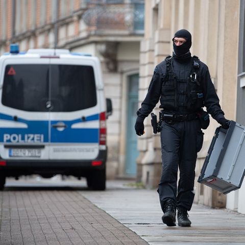 Ein Polizeibeamter geht mit einer Kiste in der Hand auf der Straße
