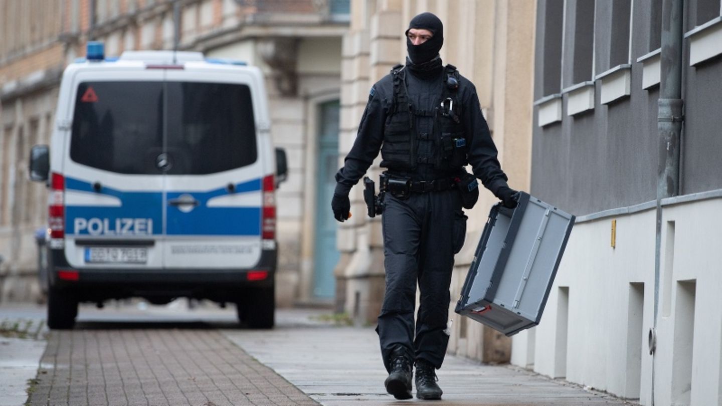 Ein Polizeibeamter geht mit einer Kiste in der Hand auf der Straße