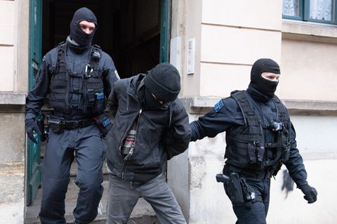 Polizisten führen bei einer Razzia einen Tatverdächtigen ab