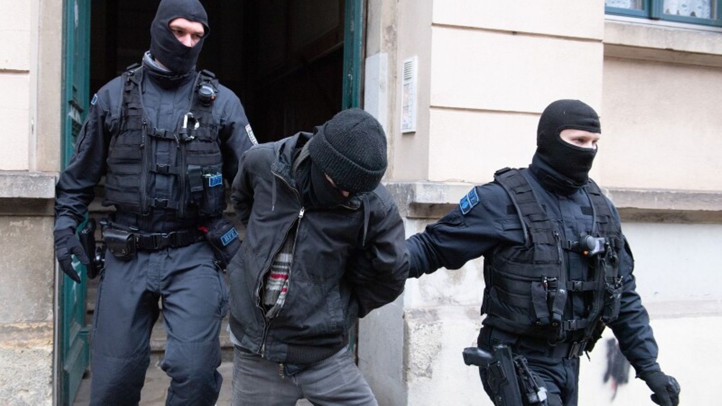 Polizisten führen bei einer Razzia einen Tatverdächtigen ab