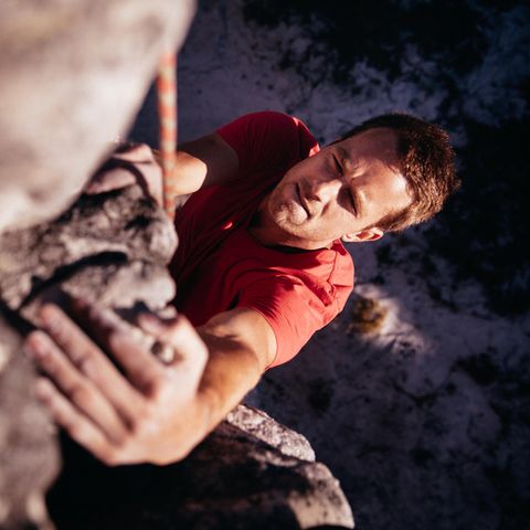 Ein junger Mann klettert an einem Seil gesichtert einen Berg hinaus