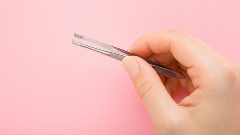 Haare am Kinn: Eine Frau hält eine Pinzette in der Hand