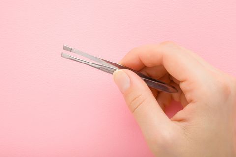 Haare am Kinn: Eine Frau hält eine Pinzette in der Hand