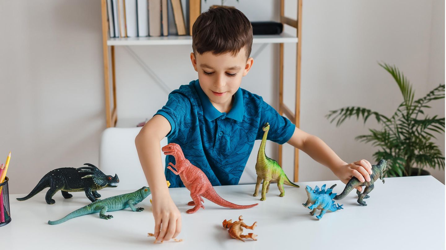 Ein Junge spielt mit Dinosauriern