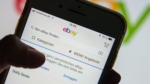 Eine Frau hält ein Smartphone mit der geöffneten Ebay-App in der Hand