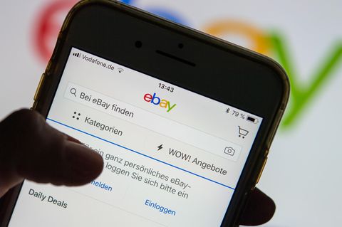 Eine Frau hält ein Smartphone mit der geöffneten Ebay-App in der Hand