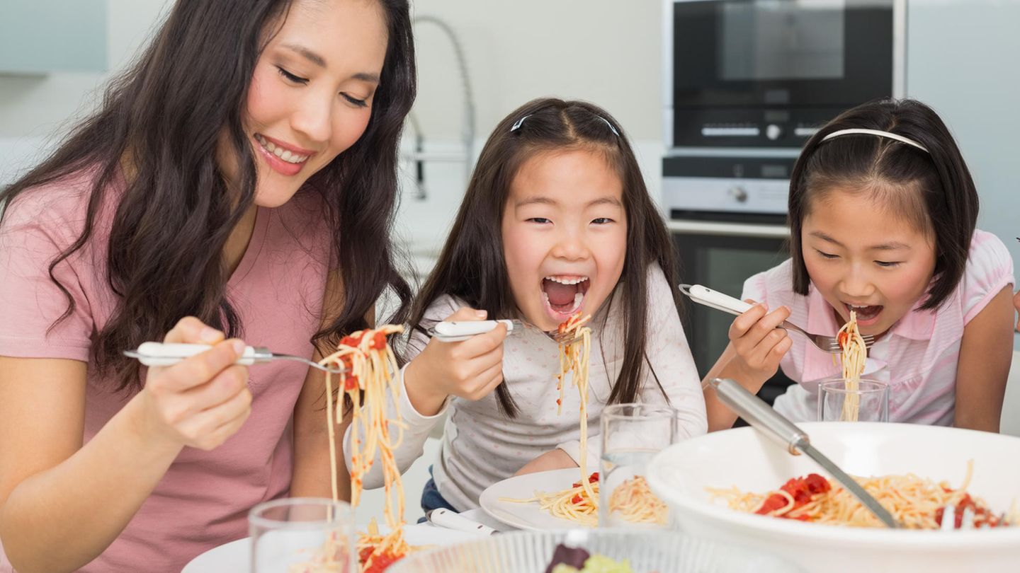 Eine Mutter und ihre zwei kleinen Töchter essen Spaghetti