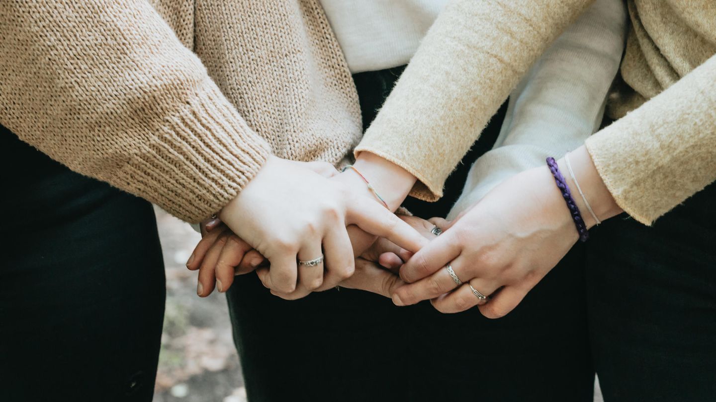 Drei Frauen halten sich an den Händen