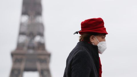 Eine Frau mit rotem Hut läuft am Eiffelturm in Paris vorbei