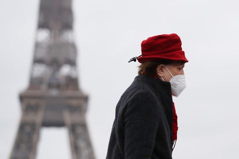 Eine Frau mit rotem Hut läuft am Eiffelturm in Paris vorbei