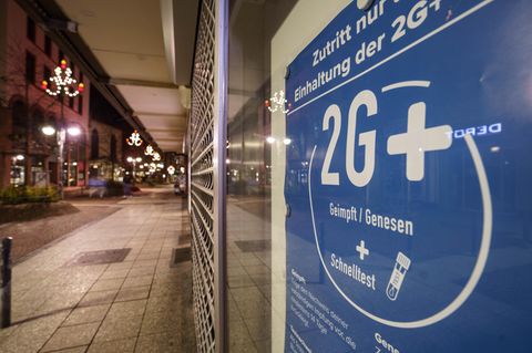 Ein 2G+-Schild in einem Schaufenster in einer leeren Straße