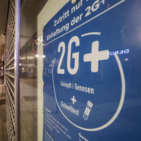 Ein 2G+-Schild in einem Schaufenster in einer leeren Straße