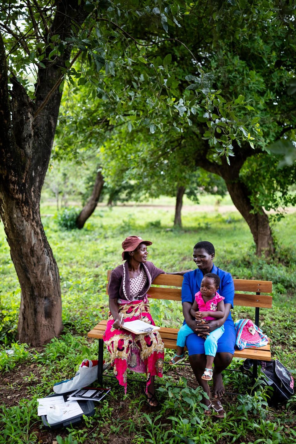 VOE STERN 52/2021 ZAKA, MSVINGO, ZIMBABWE, 24 JANUARY 2020: Elizabeth Mapaire, 56, works as a Friendship Bench counselor in the Zaka area, servicing rural clinics in the area. She is a lay health worker who is paid by the Ministry of Health but her sala... Zwei Frauen sitzen unter einem Baum auf einer Bank und unterhalten sich